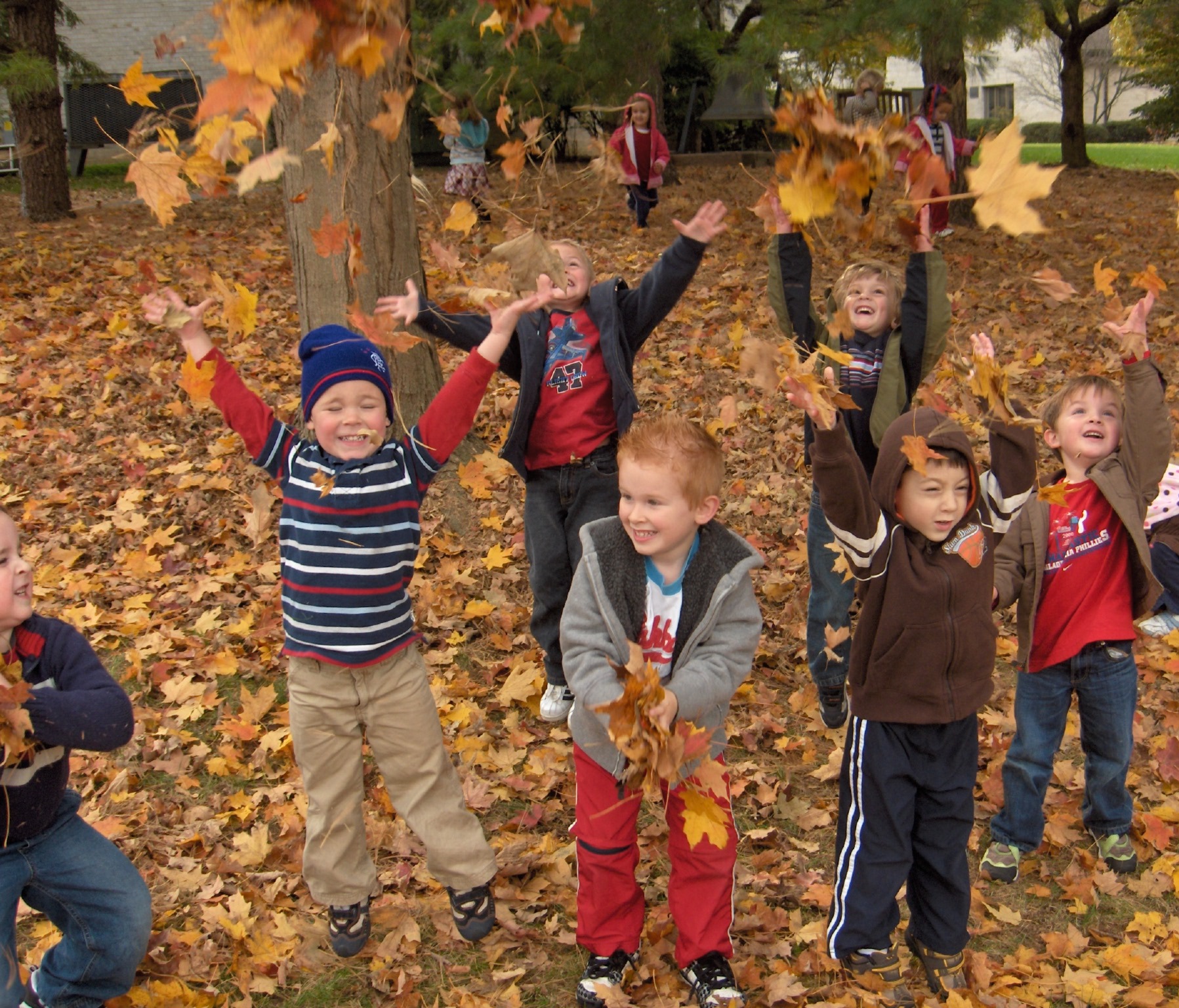 children playing in fall leaves